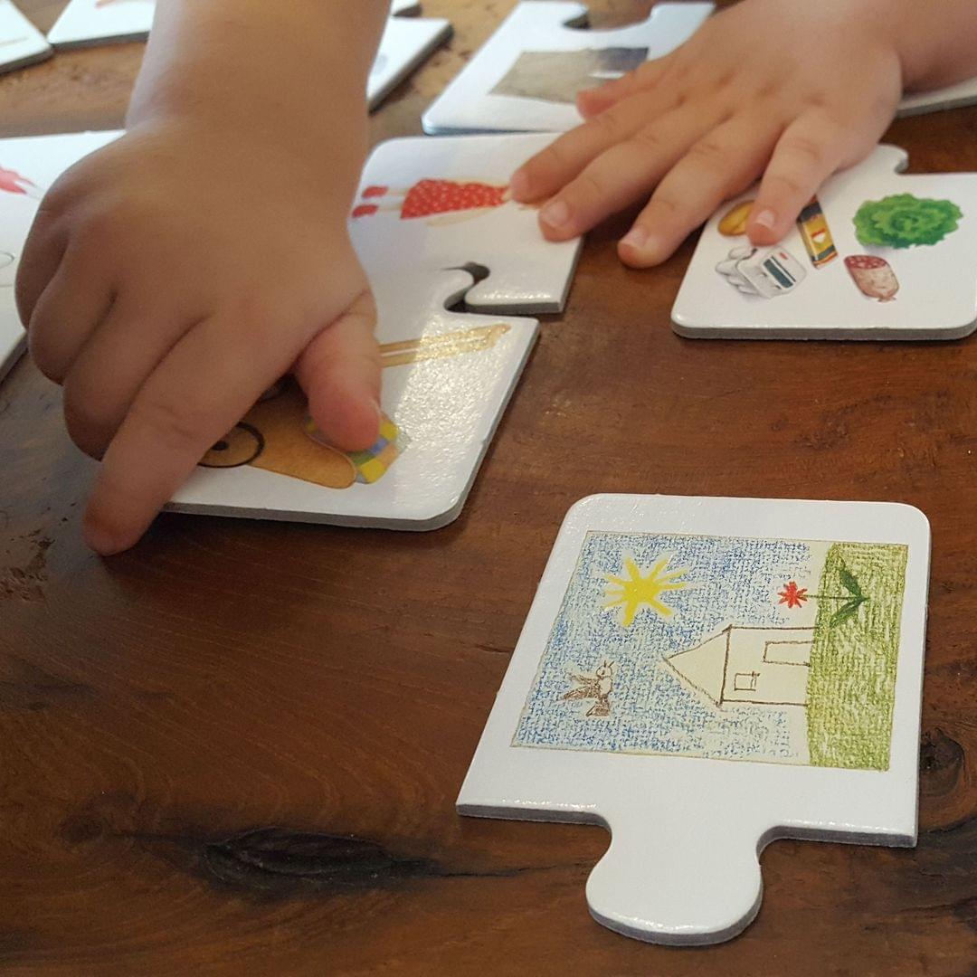 Foto von Kinderhänden, die an einem Tisch ein einfaches Puzzle machen