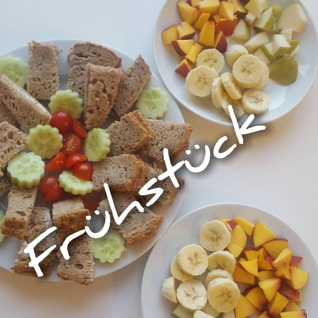 Foto eines angerichteten Frühstücks mit Gurke, Obst und Brot